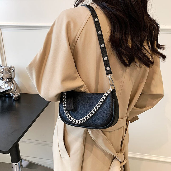 Sac à main femme noir chic avec chaîne argentée, porté de côté, parfait pour un look fashion et moderne.
