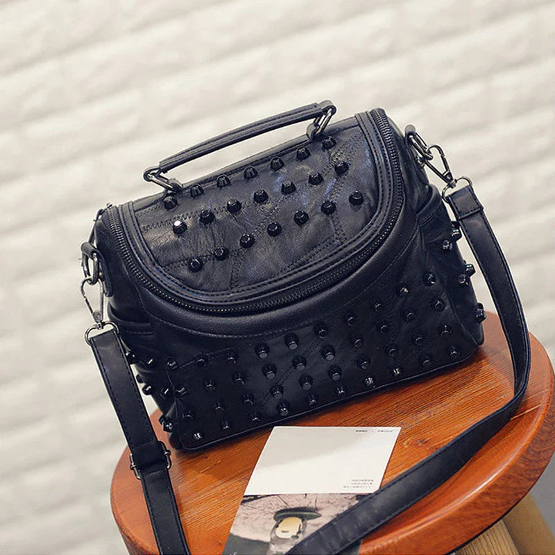 Gros plan d'un sac à main femme rock noir en cuir synthétique, clous argentés, style unique