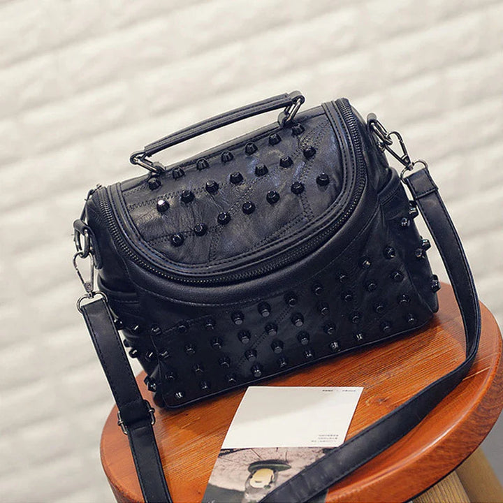 Gros plan d'un sac à main femme rock noir en cuir synthétique, clous argentés, style unique