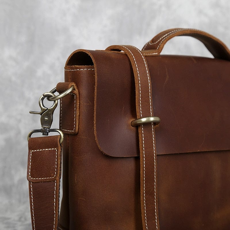 Sac à main en cuir marron foncé pour homme, ouvert, révélant ses multiples compartiments intérieurs pratiques.