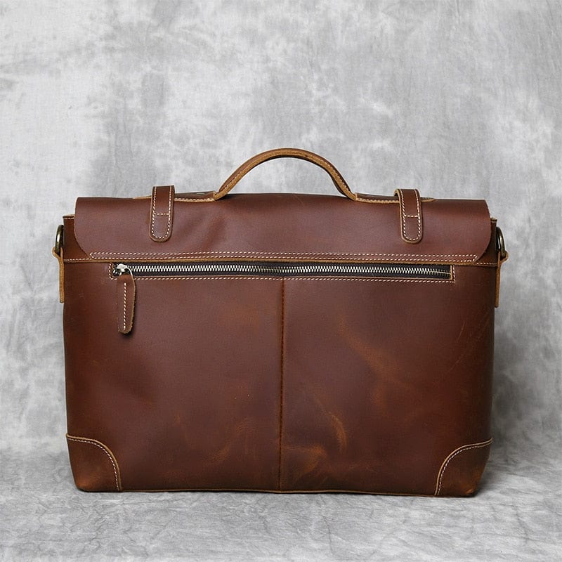 Gros plan sur la texture grainée du cuir d'un sac à main marron pour homme, soulignant sa qualité.