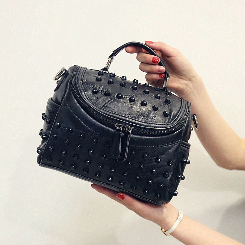 Sac à main noir clouté pour femme, élégant, en cuir, avec bandoulière réglable.