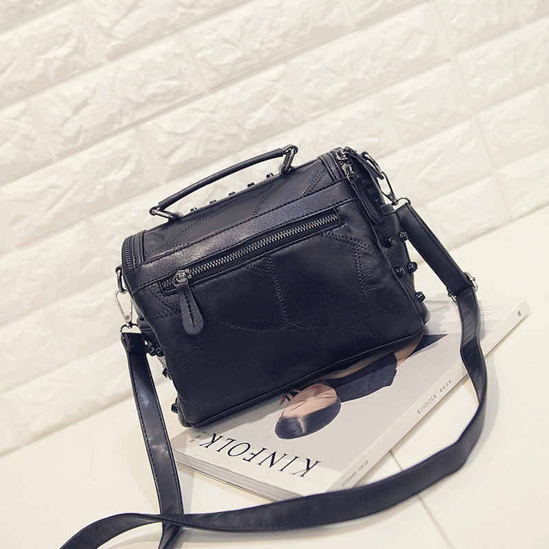 Sac à main femme noir en cuir, détail clouté, parfait pour un look audacieux et élégant.