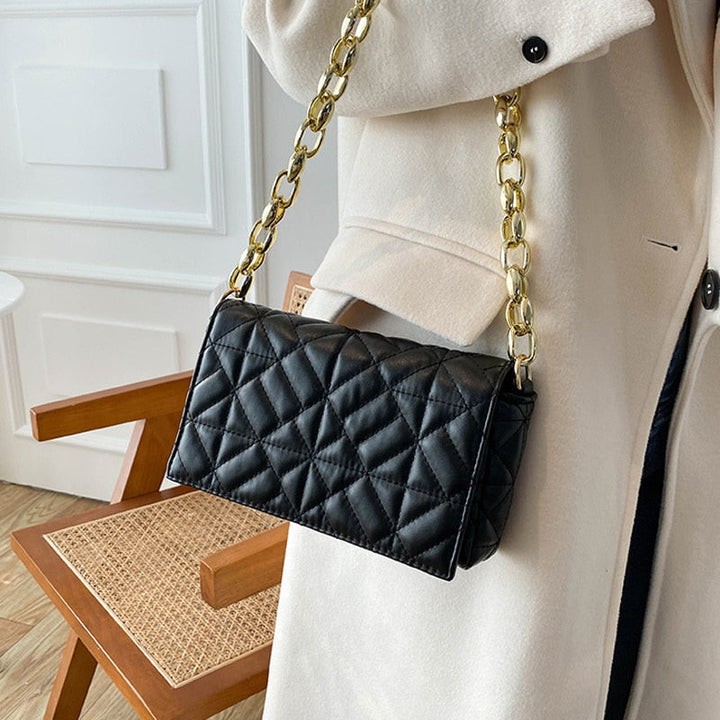 Sac femme noir sophistiqué avec anse chaîne dorée, idéal pour un look élégant.