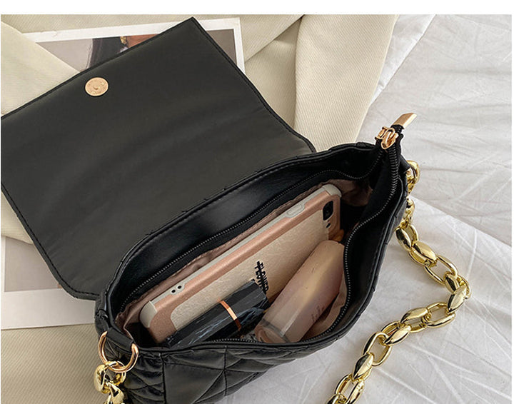 Gros plan d'un sac à main noir avec chaîne dorée, accessoire polyvalent et tendance.