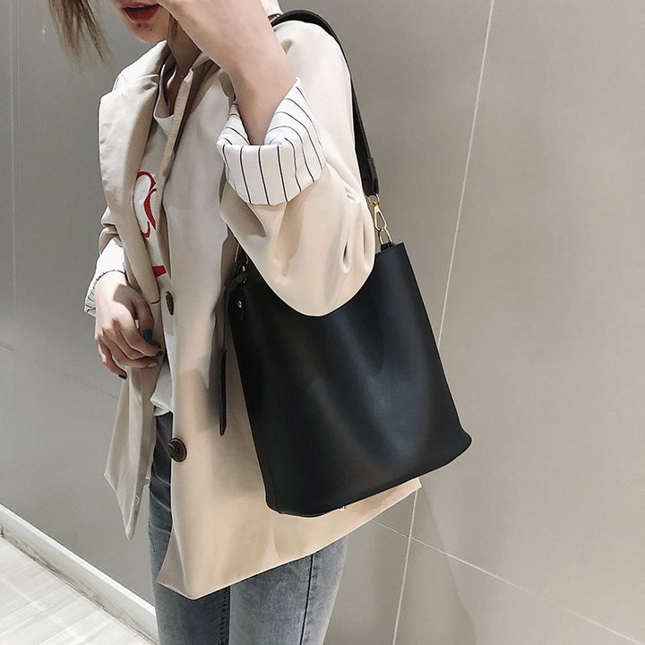 Gros plan sur la texture du sac à main épaule noir, élégant et intemporel, avec détail de la boucle dorée.