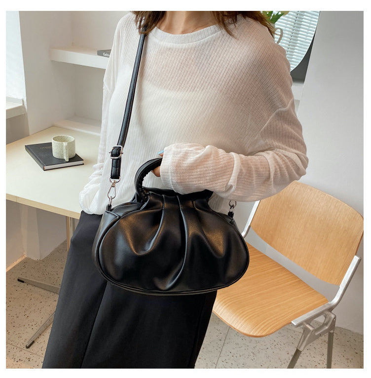 Accessoire de mode: sac rond noir élégant, portable en bandoulière ou à la main, idéal pour femme chic.