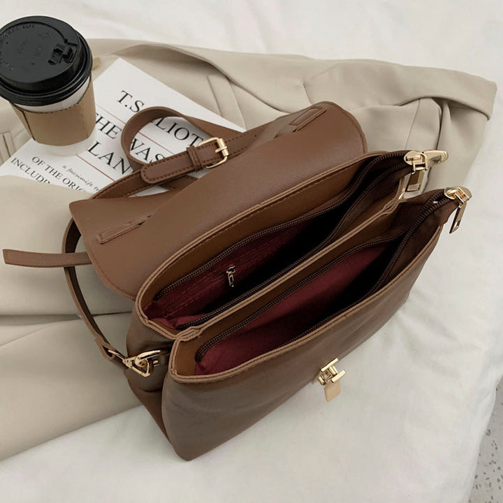 Composition d'un sac à main trapèze noir, d'un téléphone et d'accessoires, illustrant son usage quotidien