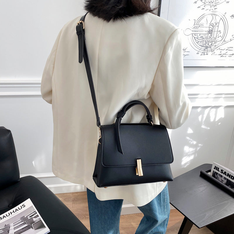 Femme élégante portant un sac à main trapèze noir sur l'épaule, accessoire mode soulignant sa tenue