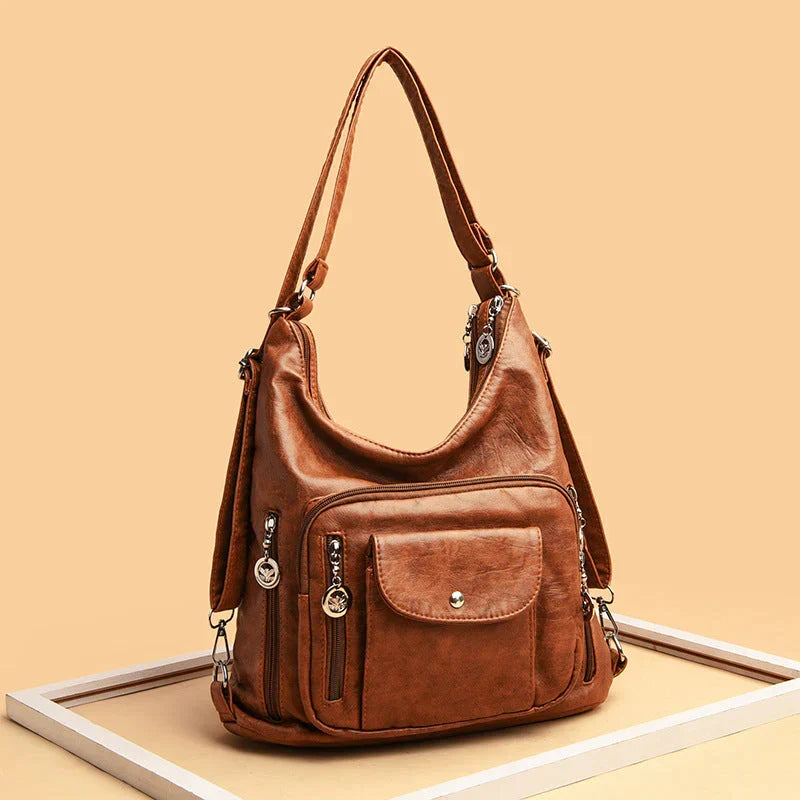 Sac à épaule femme en cuir souple, nombreux zips, style moderne et fonctionnel avec multipoches.