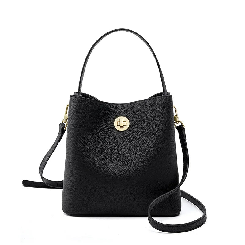 Gros plan sur le cuir grainé beige du sac seau, texture luxueuse et détails de finition dorés.