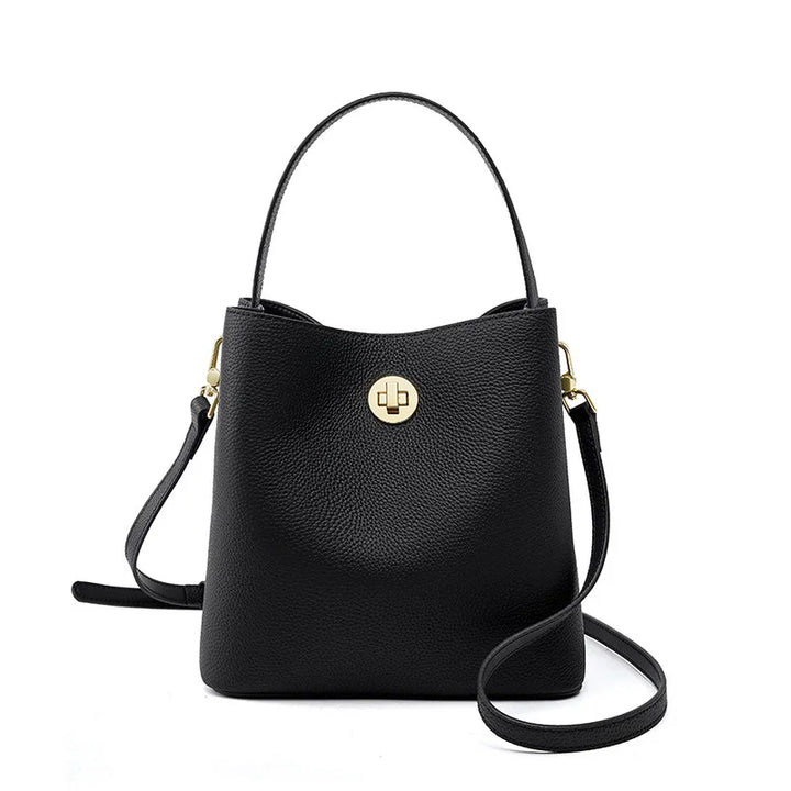 Gros plan sur le cuir grainé beige du sac seau, texture luxueuse et détails de finition dorés.