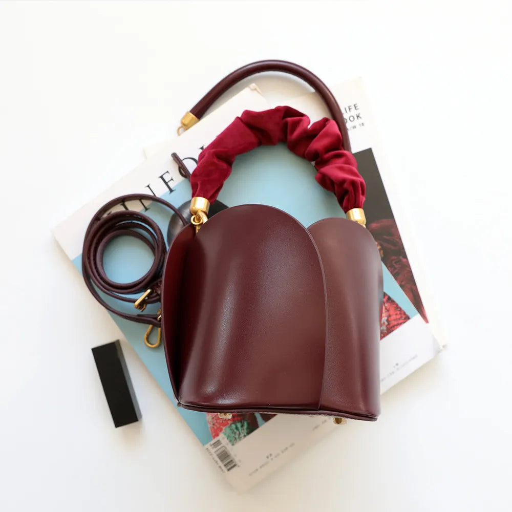 Sac seau élégant en cuir vachette marron pour femme, bandoulière ajustable. Accessoire de mode luxe.