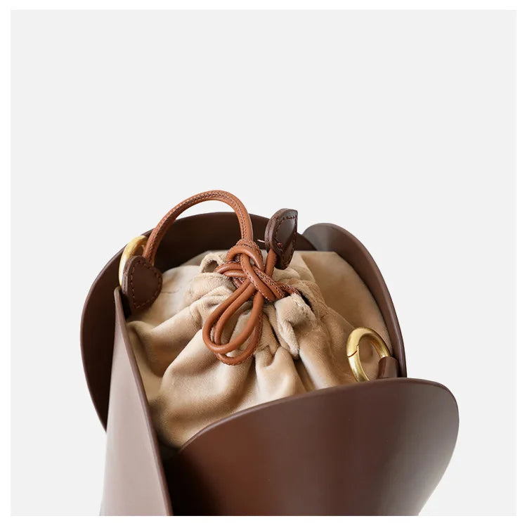 Vue détaillée du sac seau en cuir vachette rouge, avec fermeture cordon et accents métalliques dorés.
