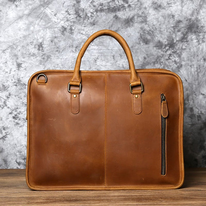 Sacoche ordinateur en cuir noir, fermetures éclair et boucles métalliques, design robuste.