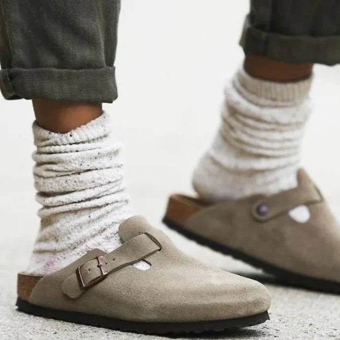 "Sandales en cuir beige unisexes élégantes sur sol en bois, boucle raffinée, design moderne et confort optimal."