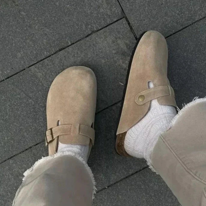 "Sandales en cuir beige unisexes élégantes sur sol en bois, boucle raffinée, design moderne et confort optimal."