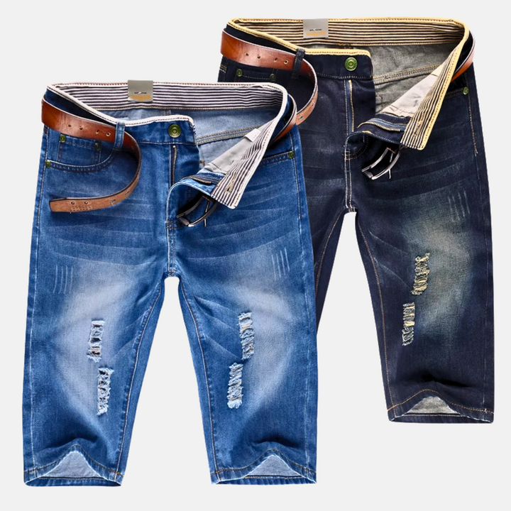 Détail short homme denim bleu avec déchirures stylisées, coupe droite, idéal pour la mode urbaine estivale.