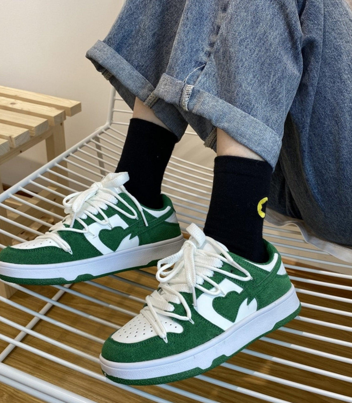 Sneakers femme blanches portées, avec motif cœur discret, pour un mélange de confort et de style tendance.