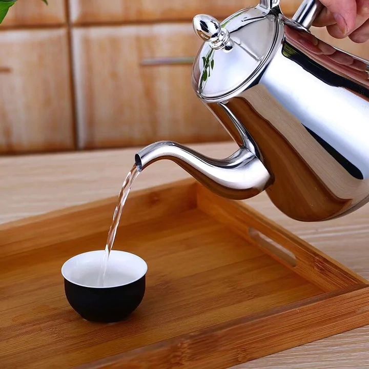 Théière induction en acier inoxydable argenté/doré avec filtre intégré, design élégant pour cuisine moderne.