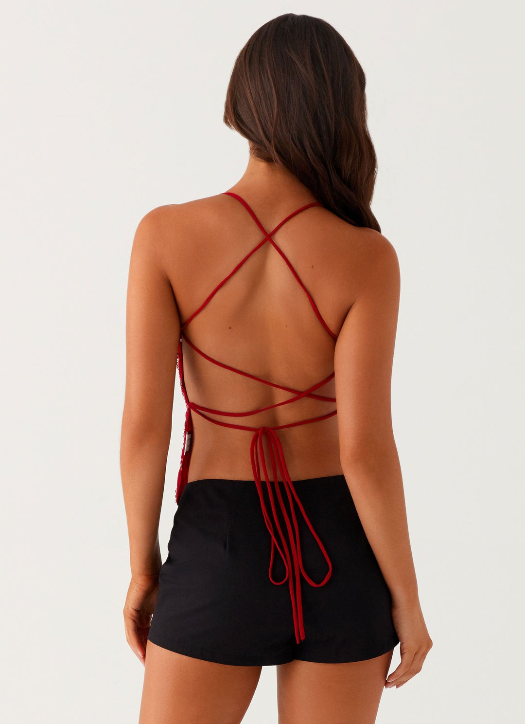 "Top cami à sequins fuchsia avec dos nu et bretelles croisées, idéal pour un look glamour et chic lors d'une soirée."