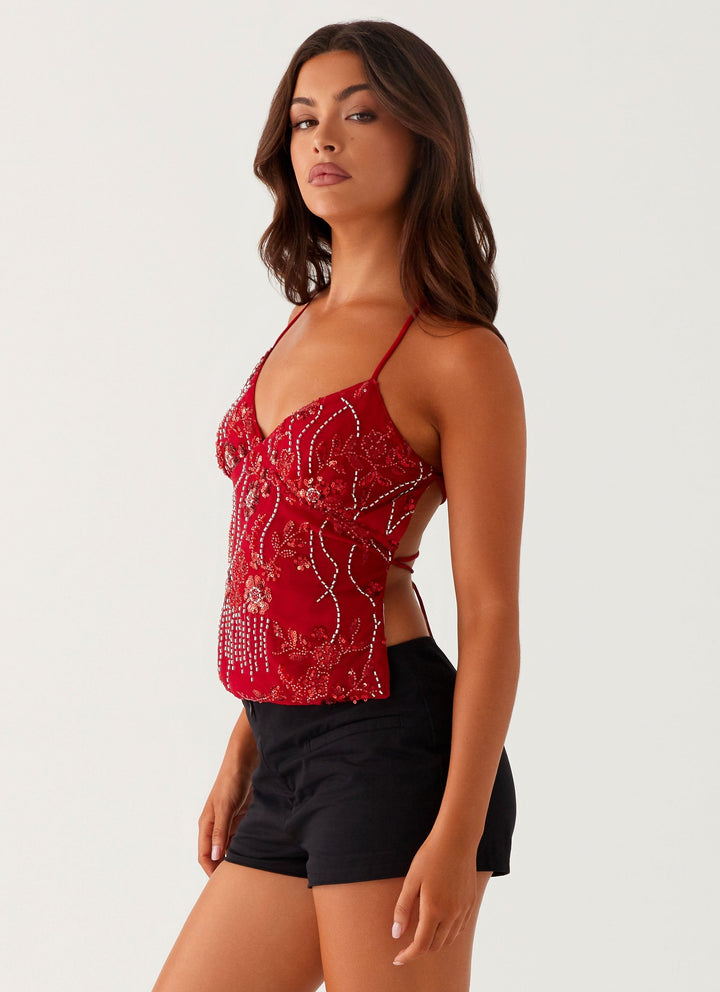 "Top cami à sequins fuchsia avec dos nu et bretelles croisées, idéal pour un look glamour et chic lors d'une soirée."