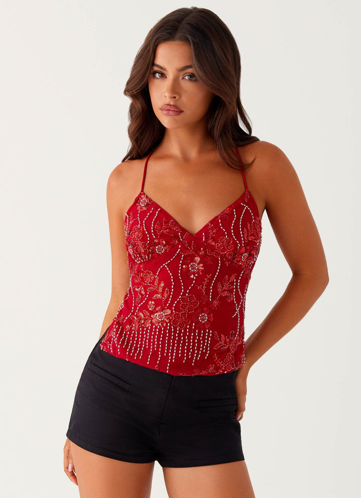 "Top cami à sequins fuchsia avec dos nu et bretelles croisées, idéal pour un look glamour et chic lors d'une soirée."