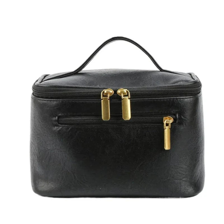 Détail de la poignée et de la fermeture éclair dorée sur une trousse de toilette en cuir PU noir