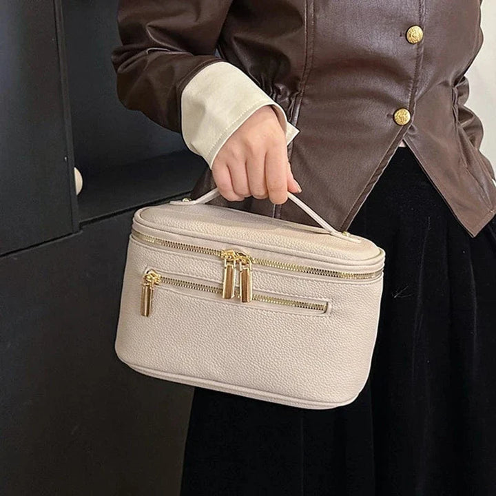 Trousse de toilette voyage en cuir PU marron, vue de côté, posée sur une coiffeuse en bois