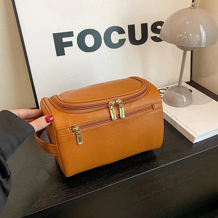 Accessoire de voyage femme: trousse de toilette rose imperméable en cuir PU, pour cosmétiques et essentiels féminins.