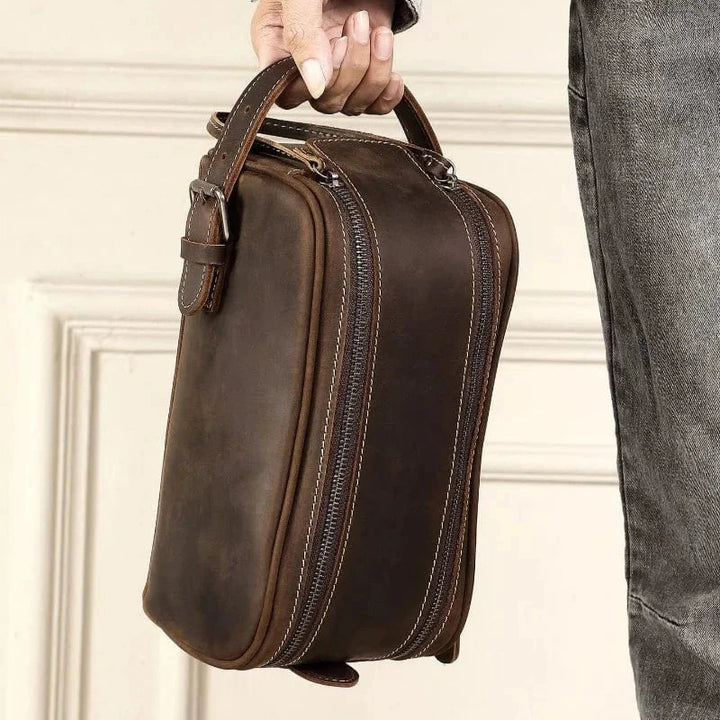 Accessoire de voyage homme : trousse de toilette en cuir marron vintage, idéale pour organiser les affaires.