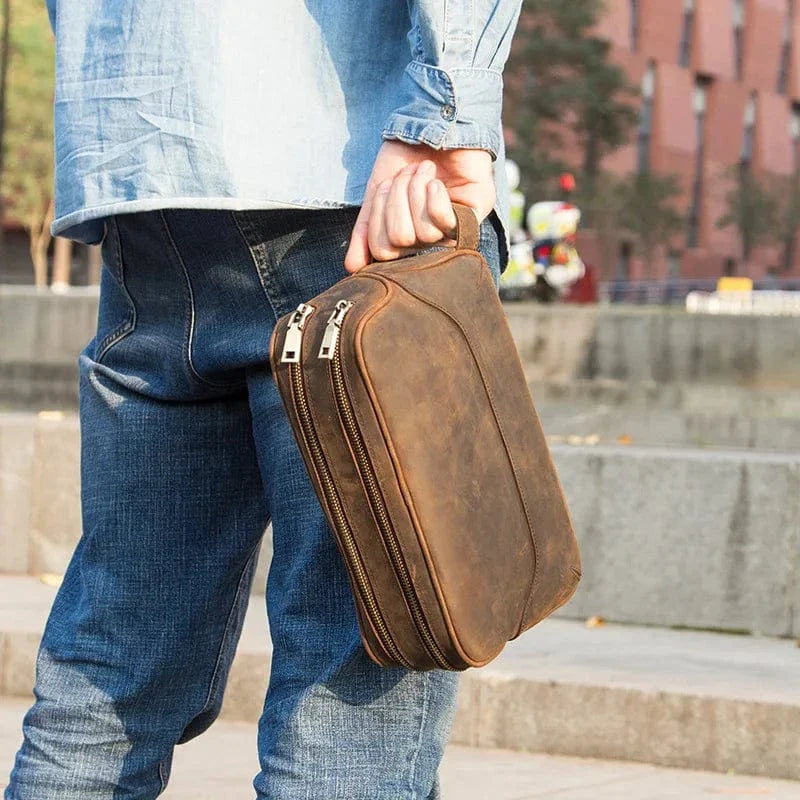 Gros plan d'une trousse de toilette homme en cuir vintage, surpiqûres détaillées, aspect vieilli et élégant