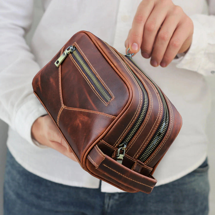 Homme tenant une trousse de toilette en cuir véritable, montrant sa taille et sa portabilité pour le voyage