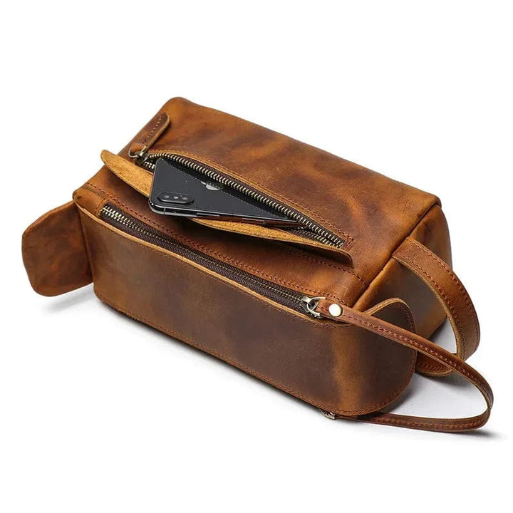 Gros plan sur le cuir vintage d'une trousse de toilette homme, texture et coutures.