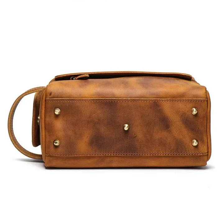 Trousse de toilette homme en cuir marron sur une valise, accessoire de voyage chic.