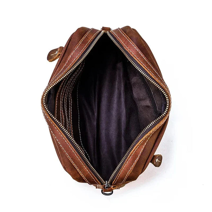 Trousse de toilette en cuir foncé pour homme, avec fermeture éclair robuste.