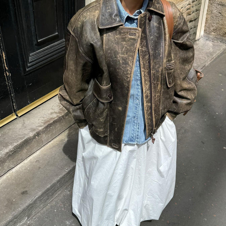 "Veste courte vintage en cuir vieilli, style rétro avec zip et poches boutonnées, parfait pour look urbain chic."