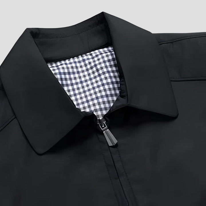 "Veste zippée imperméable homme, style urbain, couleur marine, col pointu, doublure à carreaux, fermetures discrètes."